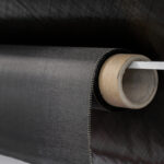 Carbon fiber composite textile material on a roll, plain carbon fiber cloth on a black background