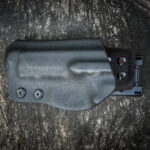 Handmade kydex holster for pistol on a grungy wood table