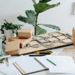 Messy workplace for designing and making cardboard boxes in a private workshop. Schematics, pencils, paper knife and special board with a cutting form.