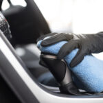 This image is a picture of wiping the car by a blue microfiber cloth with hand wearing gloves.Car wash concept.