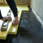 Close-up of the master cuts the size of expanded polystyrene on the floor, the process of floor insulation in the house, repair work alone.