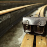 Handmade brown genuine leather satchel bag on a stadium seat.