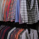 Menswear classical different suits on hangers in row in clothing shop in mall. Lots of costumes on racks in store. Business and retail concept. View of a row of ties and jackets sleeves with buttons.