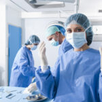 Portrait of a female surgeon, operation in the background