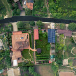 A country house in a beautiful courtyard with a solar power station made of solar panels. Concept of an eco-home with Renewable Green Energy. Top view drone shot.