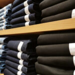 Rows of denim jeans trousers on shelves in supper store or retail store. Stack of pant jeans.
