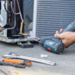 Selective focus Air Conditioning Repair, technician man hands using a screwdriver fixing modern air conditioning system