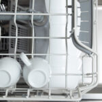 White dishes in the dishwasher. Homework with dishwasher concept.